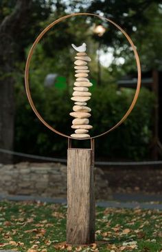 a sculpture made out of rocks sitting on top of a wooden pole in the middle of a park