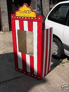 a white car parked next to a red and white striped ticket booth on the street