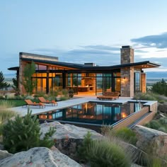 a house with a swimming pool in the middle of some rocks and plants around it