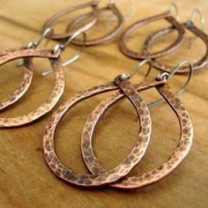 four pairs of hammered metal hoop earrings on a wooden surface