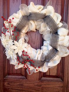 a wreath with red berries and white flowers on it is hanging on the front door