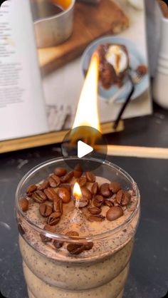 a candle that is sitting on top of a glass cup filled with coffee and nuts