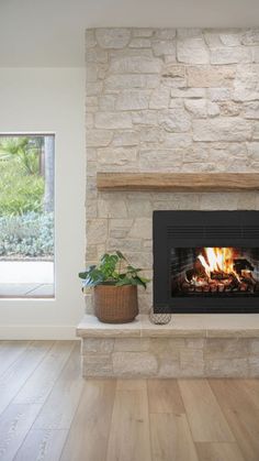 a fire place in the middle of a room with wood flooring and stone fireplace