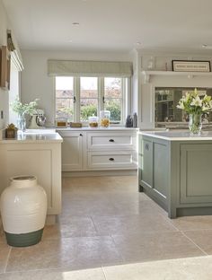 a kitchen with an island, sink and window in the center is decorated in white and green