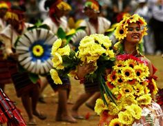 a group of people with flowers in their hair and dresses dancing on the dirt ground