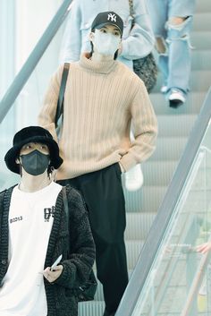 a man wearing a face mask while standing on an escalator with other people in the background