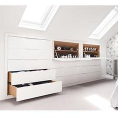 a white bed sitting under a skylight in a bedroom next to a dresser with drawers