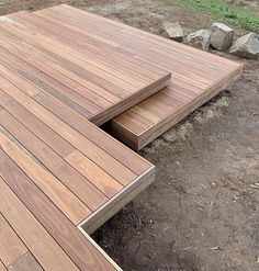 two pieces of wood sitting on top of a wooden deck next to some rocks and grass