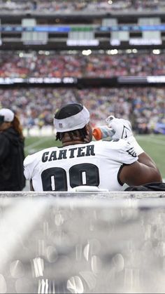 a football player sitting on the sidelines at a game with his head resting on his hands