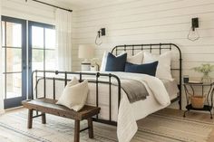 a bedroom with white walls and black iron bed frame