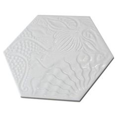 a white hexagonal tile with an intricate design on the top and bottom side