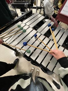 a person is playing an instrument with several mallets in front of them on the floor