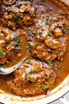 a pan filled with meat covered in mushroom gravy and garnished with parsley