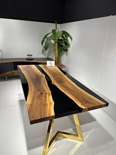 a wooden table sitting on top of a white floor next to a potted plant