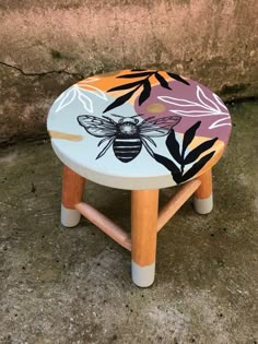 a wooden stool with a bee painted on it