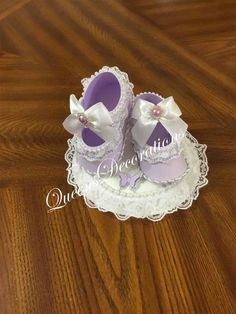 a pair of purple baby shoes sitting on top of a white doily covered cake