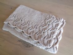 two knitted blankets sitting on top of a wooden table