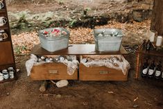 two coolers sitting on top of a wooden table filled with bottles and cans in the woods