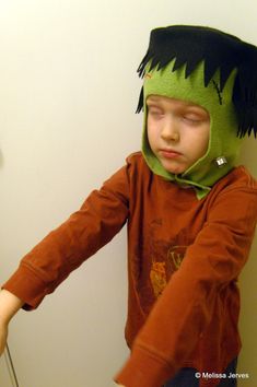 a young boy wearing a green monster hat