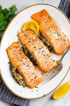 three salmon fillets on a plate with lemon wedges and parsley garnish