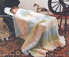 a child laying in bed under a blanket next to a toy horse and rocking chair