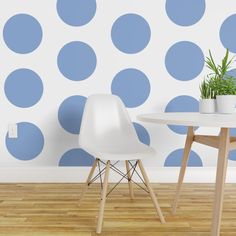 a white chair and table in front of a wall with blue polka dots on it