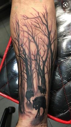 a man with an elephant tattoo on his arm and leg is standing in front of some trees