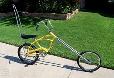 a yellow bicycle with a long handlebar attached to the front wheel is parked on a sidewalk