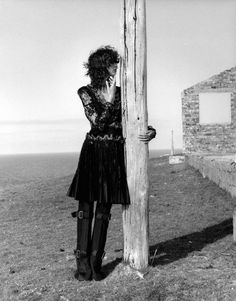 black and white photograph of woman leaning on pole