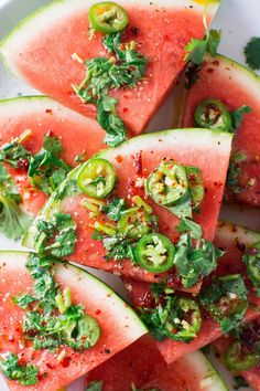 slices of watermelon with herbs and seasoning on top, sitting on a white plate