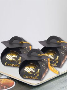 four black graduation hats on top of a white plate with gold foil lettering that says congratulations