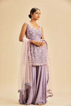 Editor's Note A lilac shimmer georgette sharara with kurta and net dupatta with resham embroidery highlighted with dabka, beads and crystals Color: Lilac Fabric: Georgette, net Components: Sharara, dupatta and kurta Occasion: Wedding Guest and festive Disclaimer: Product color may slightly vary due to photographic lighting sources or your monitor setting. Care: Dry Clean Only About the Designer Nitika Gujral’s journey with designing clothes started almost four decades back while she was still in Lilac Indian Wedding Outfits, Embroidery Sharara Designs, Lilac Kurta Women, Lilac Indian Suit, Levender Haldi Outfit, Lilac Indian Outfit, Lilac Sharara, Purple Sharara, Suit Plazo