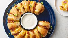 a blue plate topped with sandwiches next to a cup of ranch dressing on top of it