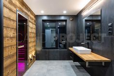 a modern bathroom with wood paneling and black walls