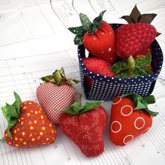 four strawberries are sitting in a basket on top of blueprinted paper with green leaves