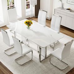 a dining room table with white chairs and a vase filled with yellow flowers on top