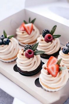 small cupcakes with cream frosting and berries on top