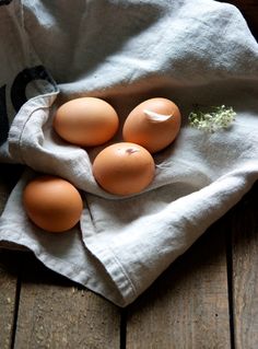 four eggs are sitting on a cloth in a bowl