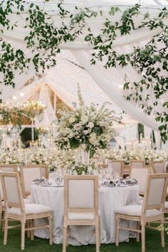 an outdoor tent with tables and chairs set up for a formal dinner or wedding reception