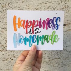 someone holding up a card with the words happiness is homemade written in multicolored ink