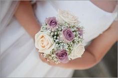 a bride holding a bouquet of white and pink roses