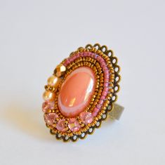 A pink glass cabochon is adhered onto a gorgeous bronze ring finding, then surrounded by delicate Miyuki seed beads and crystals to create this stunning ring.  The ring base measures approximately 3.5cm (1.5 inches) long x 2.5 cm (1 inch) across and is adjustable, so this ring fits almost any sized finger. Ready to ship! Please note that I am based in Australia - standard shipping time to the US and Europe is 2-3 weeks (longer during the Christmas season) and does not provide a tracking number. Handmade Bohemian Pink Ring, Handmade Adjustable Pink Crystal Ring, Handmade Vintage Pink Rings, Pink Bohemian Rings For Jewelry Making, Handmade Adjustable Oval Crystal Ring, Handmade Oval Crystal Ring For Jewelry Making, Pink Beaded Rings For Gift, Elegant Handmade Pink Crystal Ring, Ring Crystal