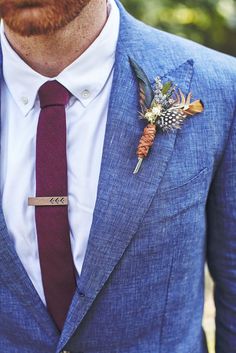 a man wearing a blue suit with a red tie and flower boutonniere