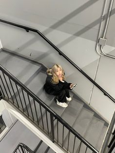 a woman sitting on top of a set of stairs holding a cell phone in her hand