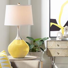 a yellow vase sitting on top of a table next to a lamp