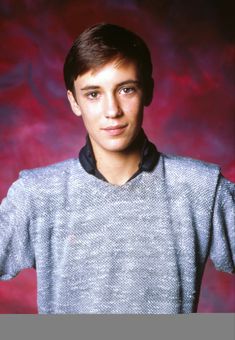 a young man posing for a photo in front of a red background