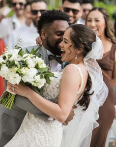 a bride and groom embracing each other in front of a group of people at a wedding