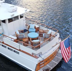 a white boat with chairs and tables on it in the water next to an american flag