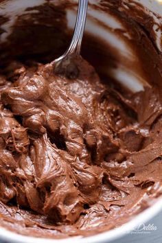 a white bowl filled with chocolate frosting and a spoon