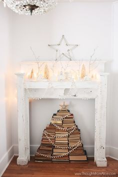 a christmas tree made out of books in front of a fireplace with candles on it